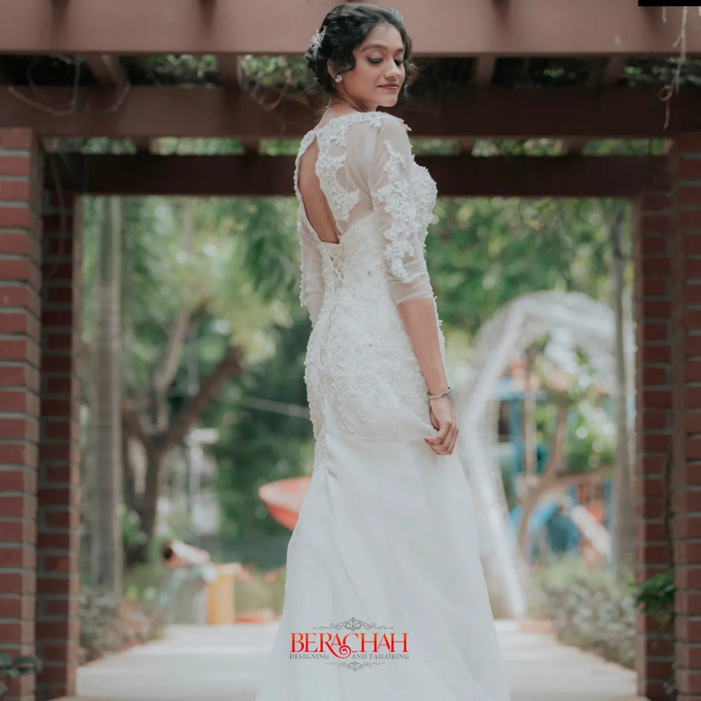 Bride in a white lace gown with an open back in a garden