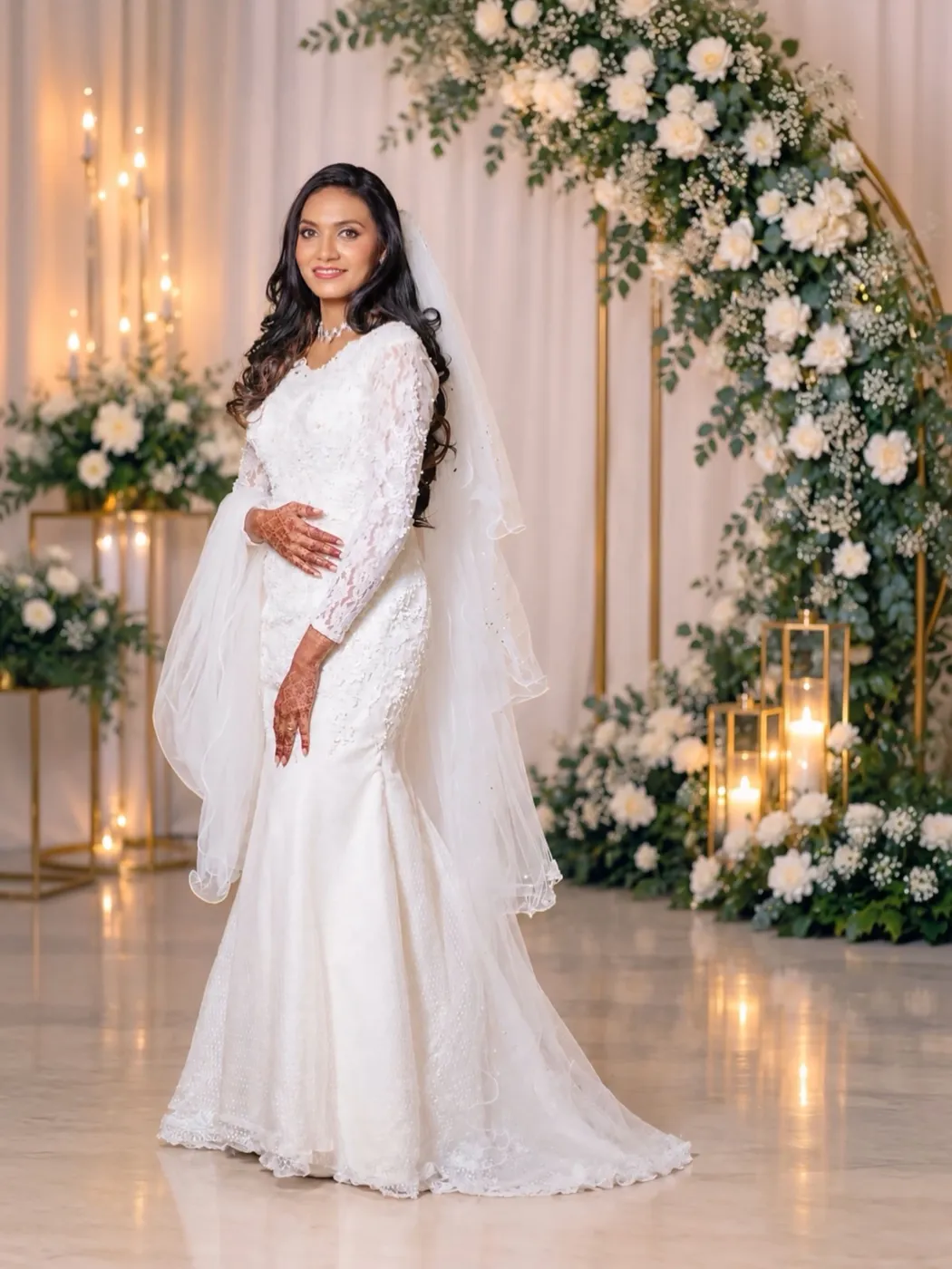 Bride in an ivory lace mermaid gown beneath a white floral arch